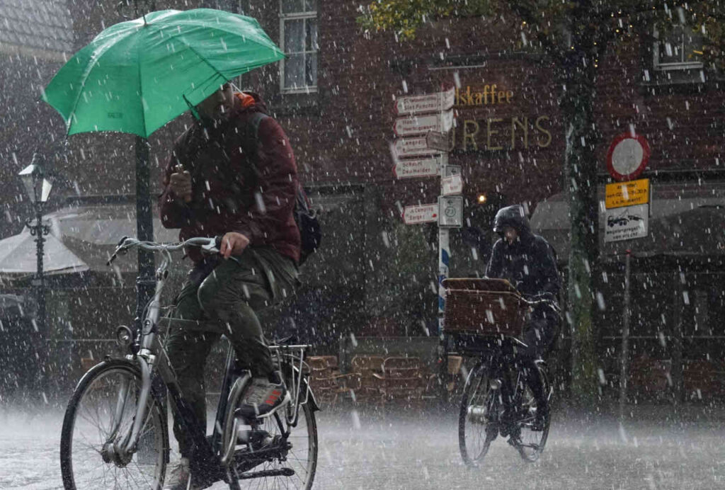 A photo of 2 cyclists riding in the rain.