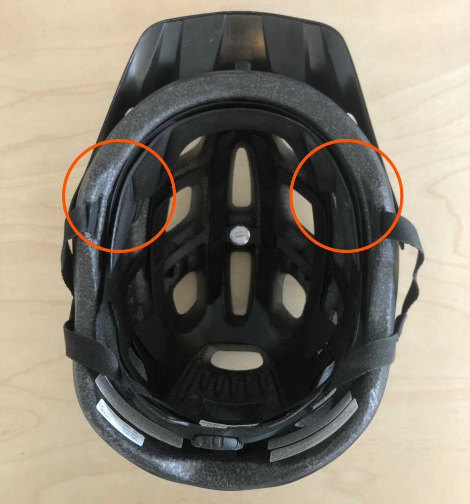 A photo of a bicycle helmet with 2 circles highlighting pads where Traction Alopecia can cause hair loss.